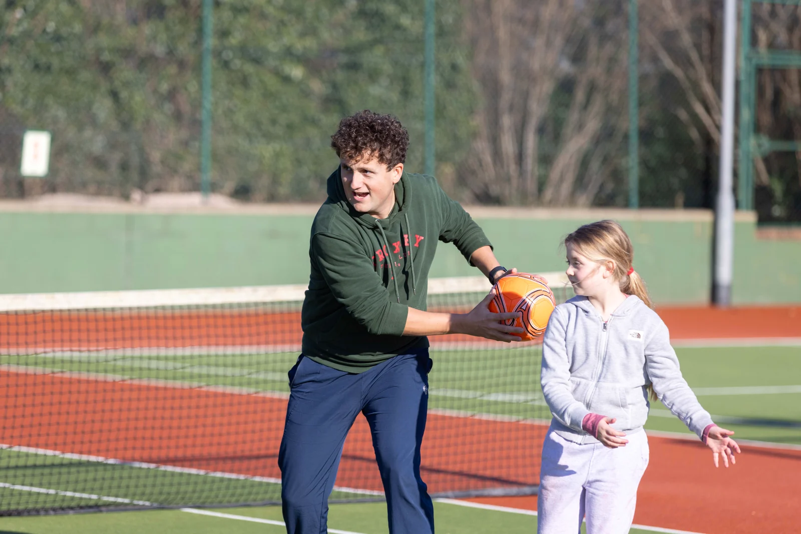 A coach passing a ball to a child during a multi-sports party game