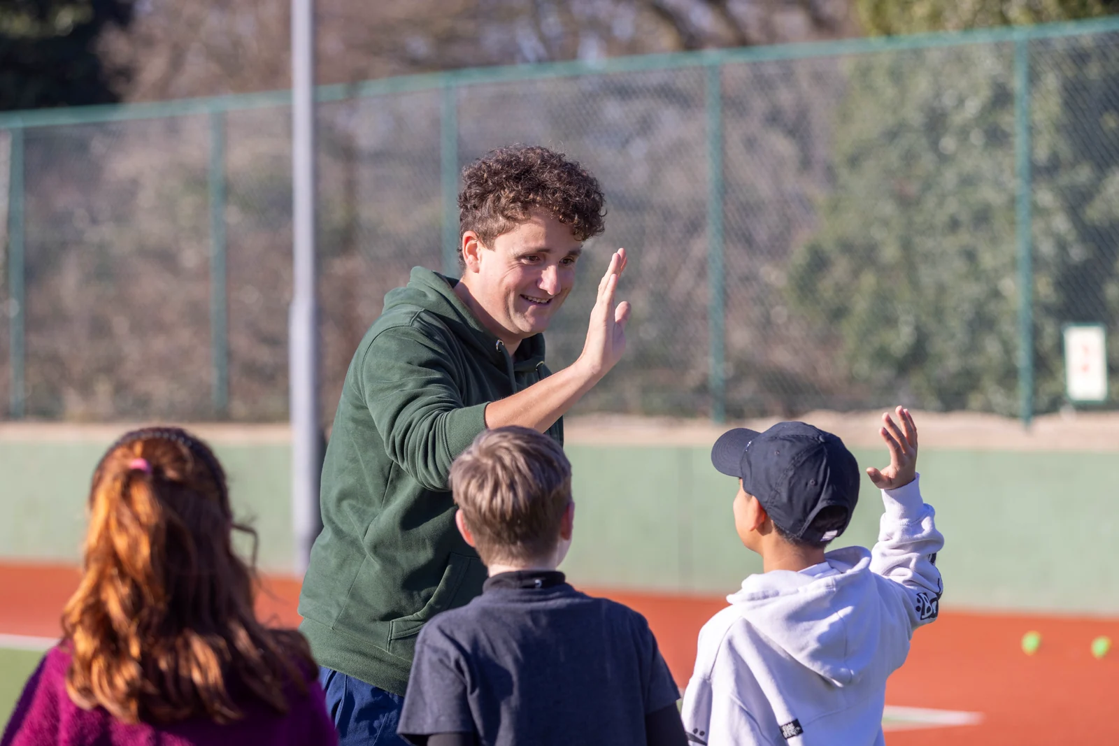 A Tennis by Sam coach high-fiving a young player